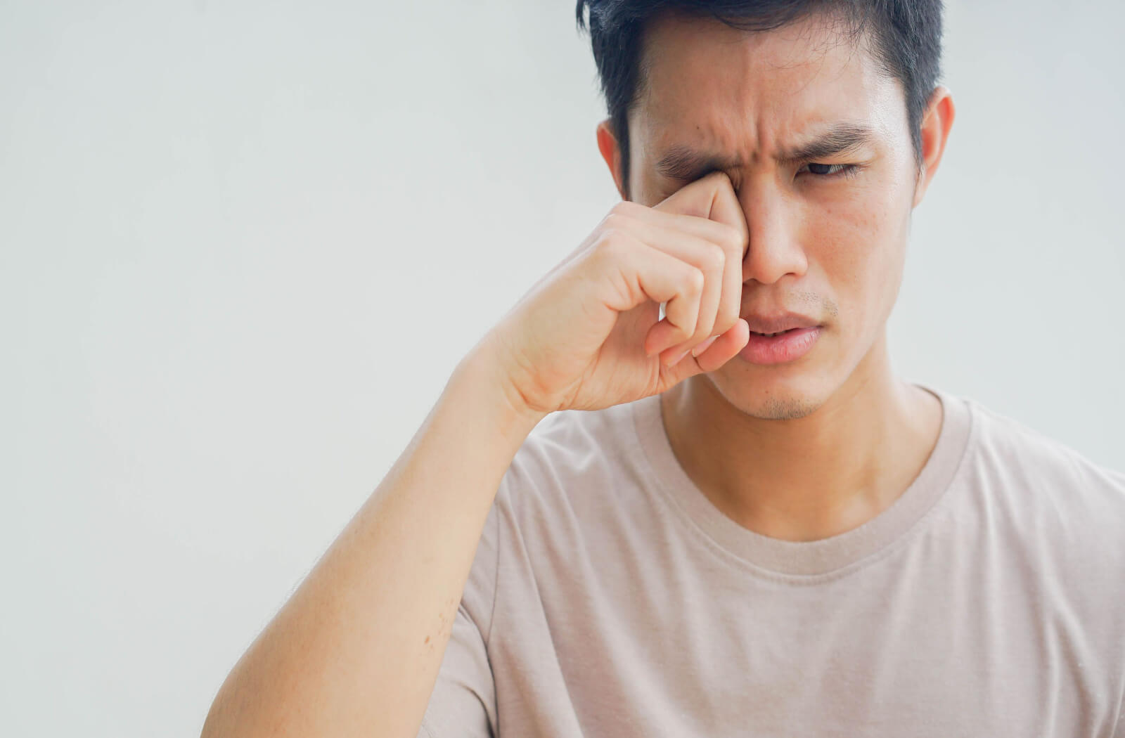 a man rubs his eyes due to itching and burning