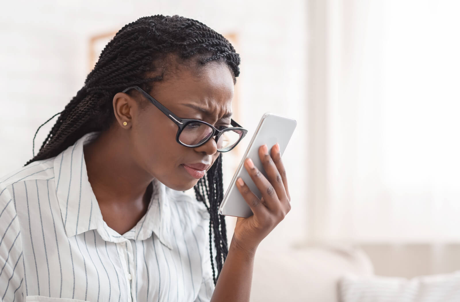 Young woman leaning closer to her phone to see its content more clearly.