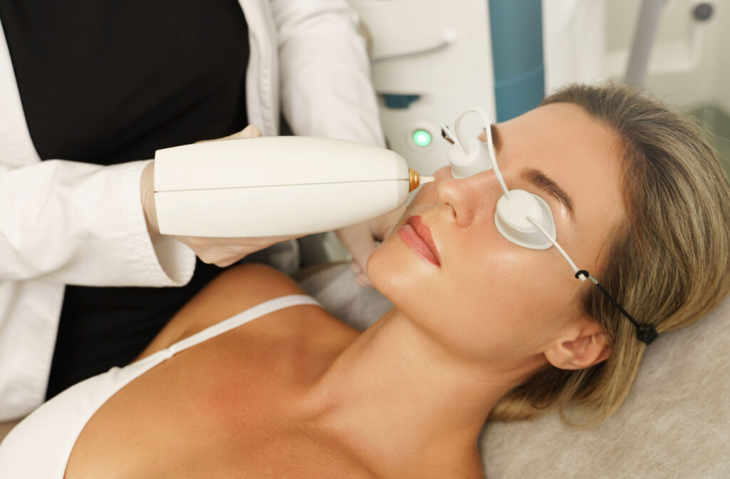 A woman laying down in an optometrist's office with her eyes covered, about to receive IPL Dry Eye treatment.