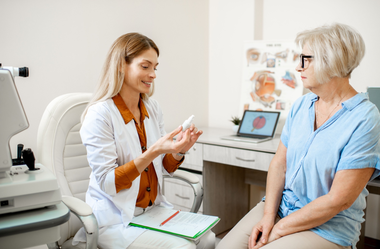 A smiling female optometrist showing a senior patient how to find the instructions on her eye drops.