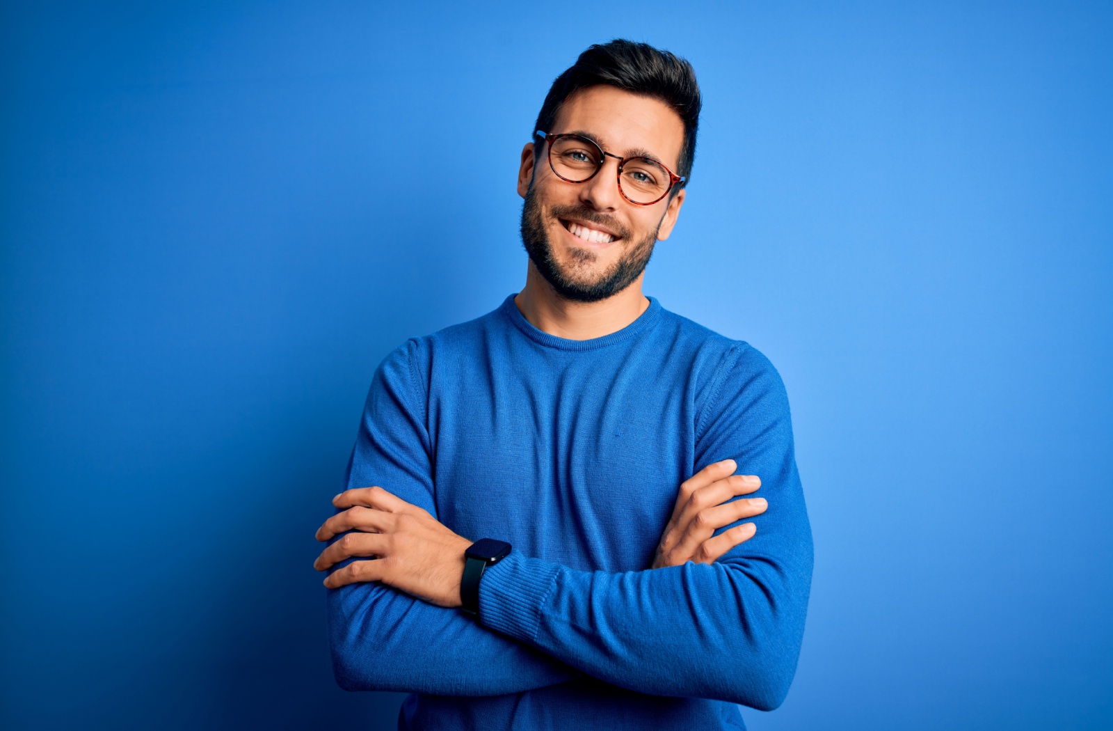 A person wearing glasses smiling, on a blue background.