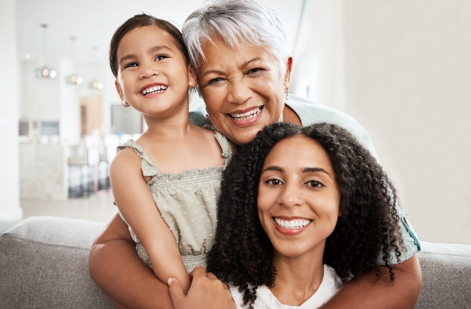A family of 3 generations cheerfully embraces one another.
